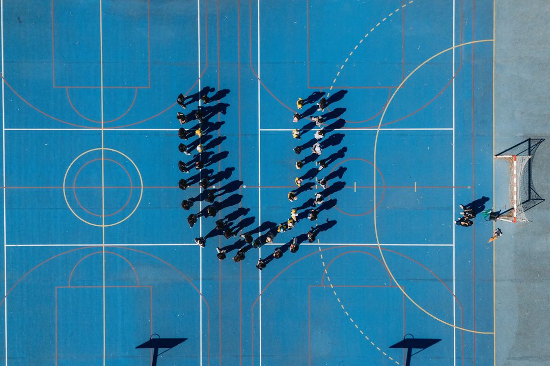 Vista aérea de participantes a formar um U num campo desportivo